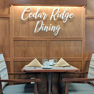 A cozy dining area at Cedar Ridge Dining, featuring a neatly set table with napkins and glassware.