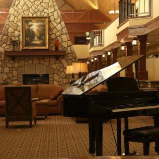 A cozy living room with a grand piano and a stone fireplace.