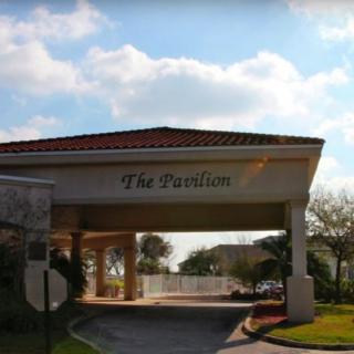 The entrance of a building labeled 'The Pavilion' under a partly cloudy sky.