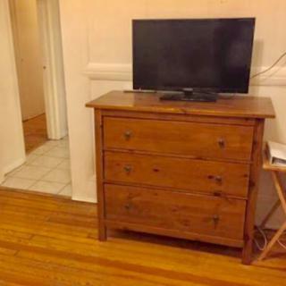 A wooden dresser with a television on top, set in a cozy living room space.
