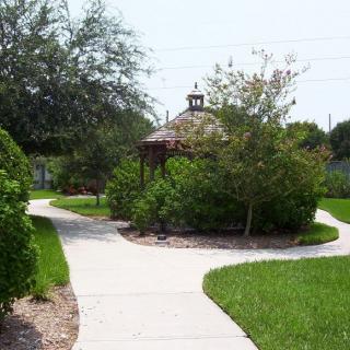 A scenic park with a winding pathway leading to a gazebo surrounded by lush greenery.