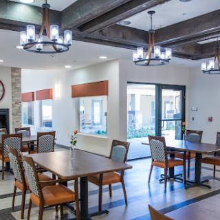 A spacious and modern dining area featuring elegant chandeliers, tables, and chairs arranged for patrons.
