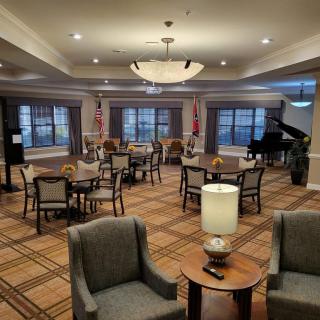 A spacious lounge area featuring a grand piano, comfortable seating, and elegant lighting.