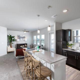 A modern open-concept kitchen with an island counter, bar stools, and pendant lighting, seamlessly connecting to the living area.