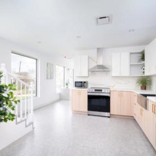 A bright and modern kitchen with minimalist design, featuring white cabinets and wood accents.