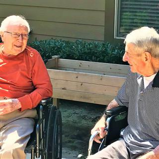 Two elderly men enjoying a conversation outdoors.