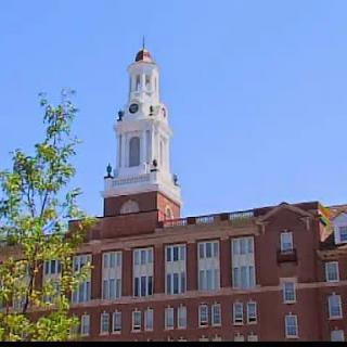 A historic brick building featuring an ornate clock tower against a clear blue sky.