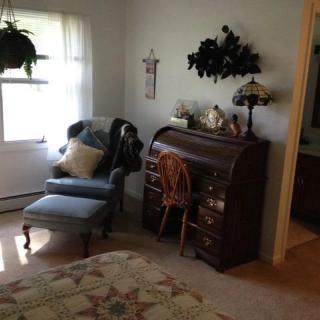 A cozy living room corner featuring a vintage roll-top desk and a comfortable armchair by the window.