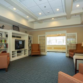A cozy living room with a television, bookshelves, and comfortable seating.
