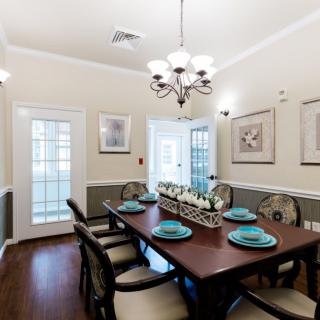 A well-decorated dining room with a chandelier hanging above a wooden dining table set for six.