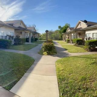 A serene residential area with a sunny pathway surrounded by houses and greenery.