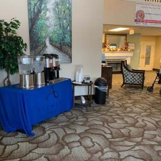 A cozy lobby with a coffee and water station, seating area, and decorative wall art.