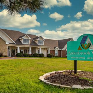 A suburban building with a manicured lawn and an informational sign under a partly cloudy sky.