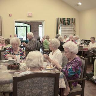 A group of seniors enjoying a meal in a community dining room.