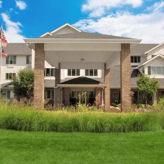 A modern building with a landscaped lawn and a blue sky background.