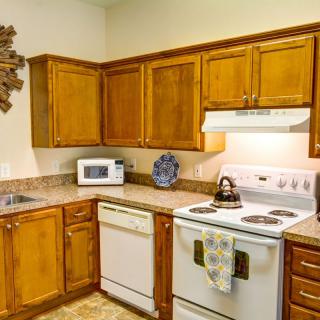 A cozy kitchen with wooden cabinets and various appliances, including a stove, oven, microwave, and dishwasher.