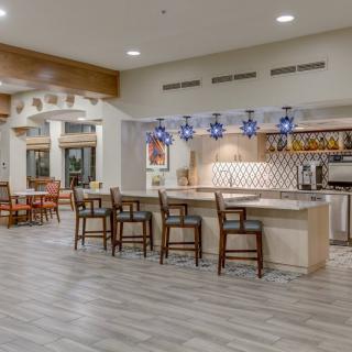 A modern kitchen and dining area with bar stools and stylish lighting.