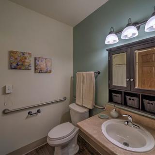 A clean and well-organized bathroom featuring a sink, mirror, and toilet with modern lighting and decor.