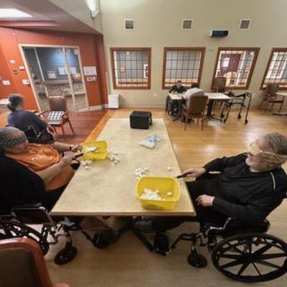 Elderly individuals in wheelchairs engaged in an activity at a nursing home.