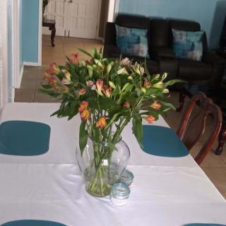 A dining table adorned with a vase of orange lilies as a centerpiece.
