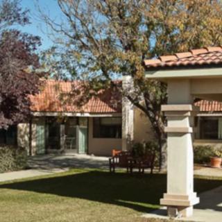 A sunny day view of a house with a well-maintained lawn and surrounding trees.