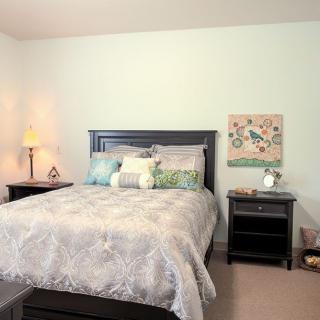 A cozy bedroom with a neatly made bed, nightstands, and decorative items.