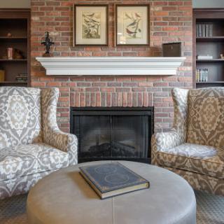 A cozy living room featuring a brick fireplace and stylish armchairs, perfect for relaxation.