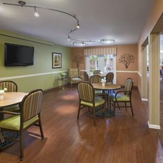 A cozy dining room with tables, chairs, and a television mounted on the green wall.