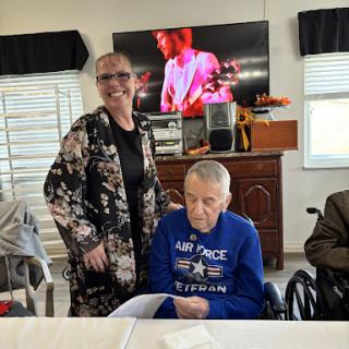 A joyful moment shared between a woman and an elderly veteran in a wheelchair, with music playing in the background.