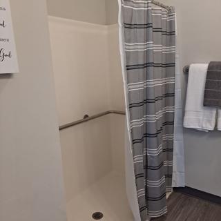A bathroom featuring a shower with a striped curtain and neatly folded towels on a rack.