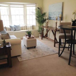 A cozy living room with a sofa, coffee table, and large windows allowing natural light.