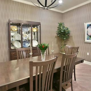 Elegant dining room with a wooden table and chairs, featuring a cabinet with dishes and tasteful decor.
