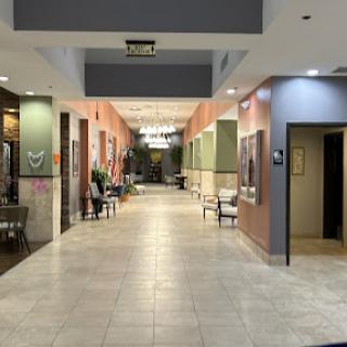 A well-lit corridor in a shopping center, featuring various storefronts and seating areas.