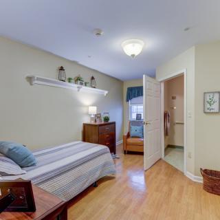 A cozy bedroom with a single bed, wooden floor, and neatly arranged furniture.