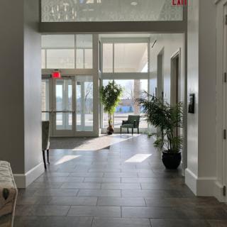 A bright and modern hallway featuring large windows, providing a welcoming atmosphere with indoor plants.