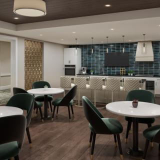 A modern dining area featuring round tables, green upholstered chairs, and a kitchenette with elegant lighting.