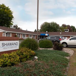 The entrance of a residential property featuring a sign and neatly landscaped grounds.