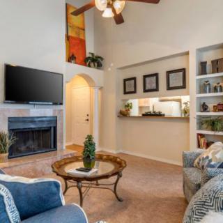 A cozy living room with a fireplace, comfortable seating, and a TV mounted above the mantel.