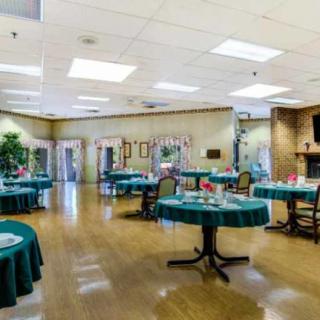 A spacious dining area with multiple tables and chairs set up, featuring green tablecloths and elegant decor.