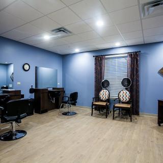 A well-organized salon room with blue walls, featuring chairs and mirrors.