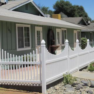 A residential house with a white picket fence and a small patio area.