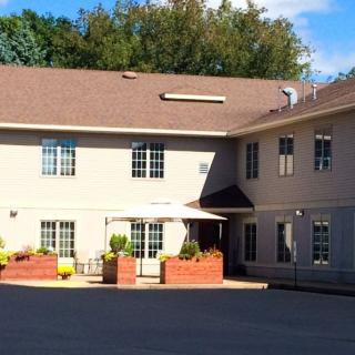 A two-story residential building with a paved driveway and potted plants at the entrance.