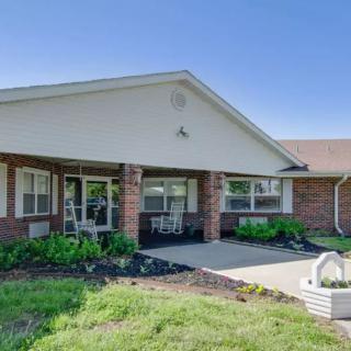 A single-story brick residential building with a landscaped front yard and driveway.