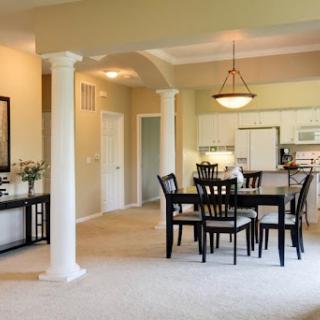 A spacious open-concept dining area connected to the kitchen, featuring elegant furniture and architectural columns.
