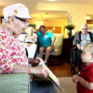 A heartwarming moment of connection between a child and an elderly woman as they share a story in a care home.