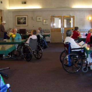 Elderly people in wheelchairs gathered in a nursing home common area.