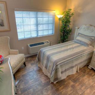 A cozy bedroom with a single bed, comfortable chair, and soft lighting.