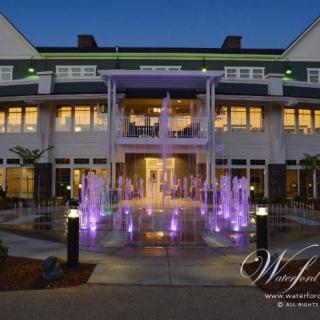 Illuminated hotel entrance with a colorful fountain at dusk.