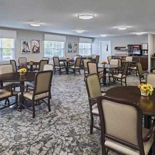 A spacious dining area with neatly arranged tables and chairs, featuring floral centerpieces and modern artwork on the walls.