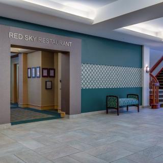 The image showcases the entrance to a modern restaurant with a seating area and staircase in the lobby.